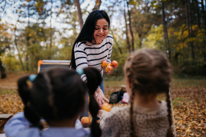 Woman handing children fresh fruits outside