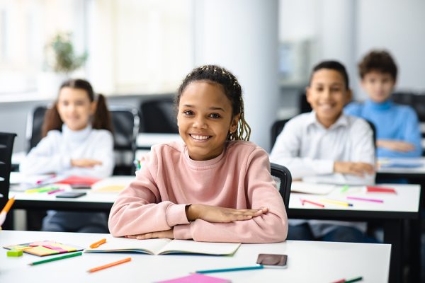 Portrait of small girl sitting at desk in classroom